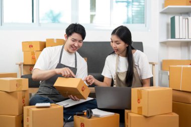 Paket detaylarını tartışan bir çift, rahat bir çalışma alanında takım çalışması ve işbirliğini yansıtıyor.