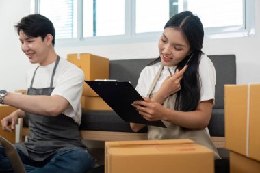 Bir çiftin e-ticaret görevleri vardı, biri telefondaydı, diğeri de ev ofisteki paketleri düzenliyordu..