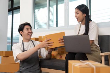 Bir çift, paketleri değiş tokuş ederken, takım çalışmalarını ve modern bir ofiste olumlu etkileşimlerini vurgularken neşeli bir anı paylaşıyor..