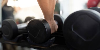 Odaklanmış bir birey, spor salonundaki sağlık ve zindeliği vurgulayan bir halterle güç eğitimine girişir..