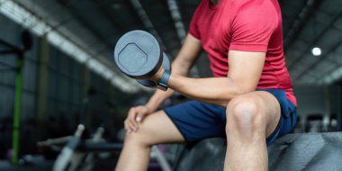 Bir birey otururken halterle kuvvet eğitimine girer, sağlığını ve fiziksel kondisyonunu destekler..