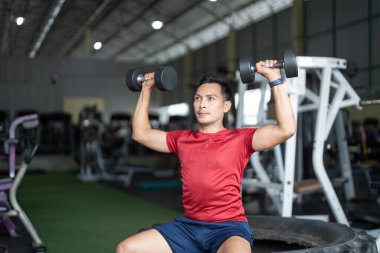 Kendini adamış bir adam spor salonunda halter ütülüyor. Fiziksel kondisyon yoluyla güç ve sağlığını ön plana çıkarıyor..