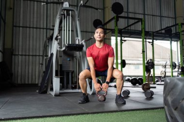 Formda bir adam salıncak sallar, spor salonunda tüm vücudunu güçlendirir..