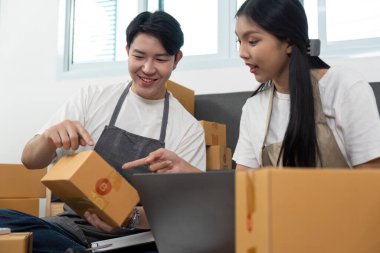 Genç bir çift, iş yerlerindeki paketleri sıralarken e-ticaret stratejilerini heyecanla tartışıyor..