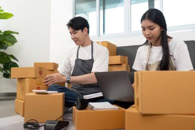 Ev ofisinde birlikte çalışan, paketleri düzenleyen ve online işlerini yöneten bir çift. Atmosfer verimli ve destekleyici..