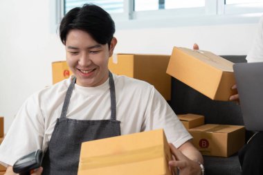 Birkaçı envanteri kontrol edip lojistiği tartışırken, parlak bir çalışma alanında paketlerle çevrili, takım çalışmasını ve verimliliğini yansıtıyor..