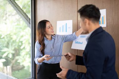 Bir iş adamı, takım çalışması ve iletişimi vurgulayarak proje sonuçlarını bir meslektaşına sunar.