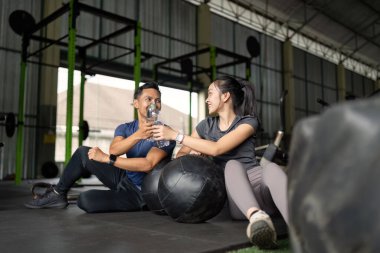 İki arkadaş ferahlatıcı bir su molası verip spor salonunun atmosferinde spor ve arkadaşlıklarını kutluyorlar..