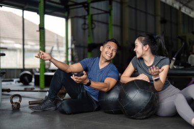 İki arkadaş spor salonundaki antrenman sırasında gülüşmeler ve cesaretlendirmeler paylaşıyor, dostluk ve fitness gösterisi yapıyorlar..