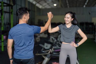 İki arkadaş spor salonundaki başarılarını bir beşlikle kutluyor, dostluk ve motivasyon gösterisi yapıyorlar..