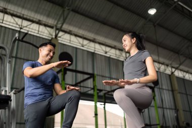 Denge egzersizleri yapan iki arkadaş, destekleyici bir spor salonunda fitness ve arkadaşlığı teşvik ediyorlar..