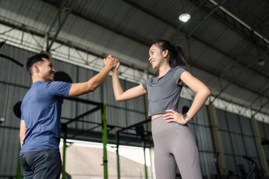 Spor salonundaki iki arkadaş arasında keyifli bir an, idmandan sonra beşlik çakmak, fitness ve arkadaşlığı teşvik etmek..