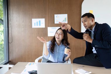 İki profesyonel modern ofis ortamında iş başarılarını sevinçle kutluyor, takım çalışması ve başarı sergiliyorlar..