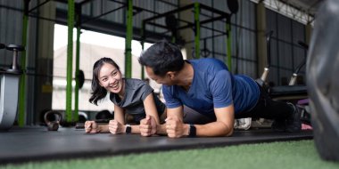 Spor salonunda tahtayla antrenman yapan iki arkadaş arasında neşeli bir an. Sağlık, spor ve arkadaşlığı teşvik etmek için..