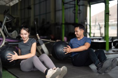 Spor salonunda tıp topu antrenmanına katılan iki arkadaş, fitness ve takım çalışmasını destekliyor..