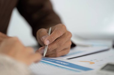 Finansal karar alma sürecindeki işbirliğini vurgulayan, bir müşteriyle mali raporu inceleyen bir profesyonel..