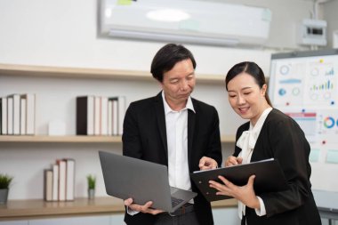 Çağdaş bir ofis ortamında dizüstü bilgisayardaki verileri incelerken iki profesyonel işbirliği yapar ve görüşlerini paylaşır.