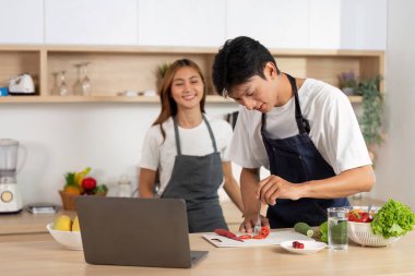 Modern bir mutfakta, bir çift birlikte akşam yemeği hazırlamaktan zevk alır. Kahkahalar ve taze malzemelerle çevrili..