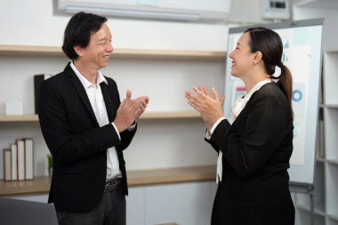 Çağdaş bir ofis ortamında başarı ve işbirliğini kutlayan iki iş adamı aynı neşeli etkileşimi paylaşıyor..