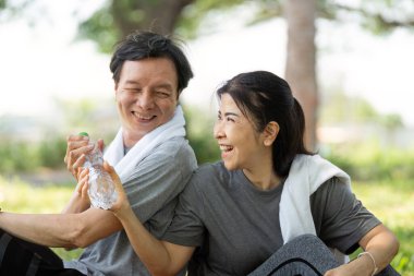 Bir çift, spor yaptıktan sonra su molası verip aktif yaşam tarzlarını vurgularken keyifli bir anı paylaşıyor..