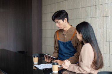 Bir tablet ve dokümanları inceleyen iki girişimci, modern bir kafe ortamında beyin fırtınası yapıyorlar..