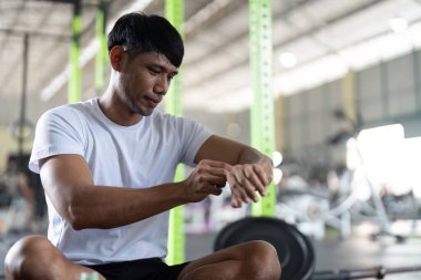 Kararlı erkek sporcu, spor ölçümlerini takip etmek için ince ayar yapıyor. Spor salonundaki spor teknolojisini vurguluyor.