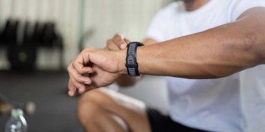 Bir adam, sağlık ve sağlıktaki teknolojik rolleri vurgulayarak, fitness ölçümlerini takip etmek için akıllı saatini inceler..