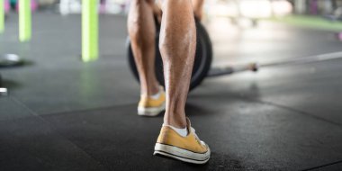 Odaklanmış erkek sporcu ağırlık kaldırmaya hazırlanıyor. Spor salonunda güç ve kararlılık gösteriyor..