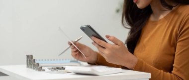 Bir kadın akıllı telefonuyla finans işlerini yönetirken, harcamaları takip ederken ve bütçeyi etkin bir şekilde değerlendirirken....