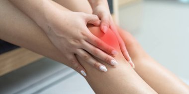 Bir kadın eklem sağlığı için endişe ederek dizini acıdan bastırıyor. Hareket ve yaralanma sorunlarını vurgular.