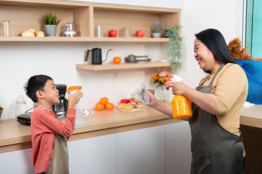 Bir anne ve oğul, ev işlerinde takım çalışmasının ve sorumluluğun altını çizerek mutfağı temizlemeye hazırlanırken keyifli bir anı paylaşıyorlar..