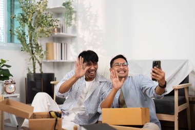 İki adam yeni evlerini kutlarken ve deneyimlerini paylaşırken neşeyle selfie çekiyorlar..