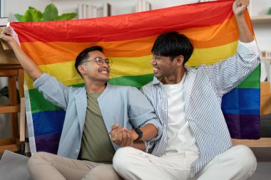 Gökkuşağı bayrağını tutan iki adam, sıcak yaşam alanlarında sevgilerini ve gururlarını ifade ediyorlar..