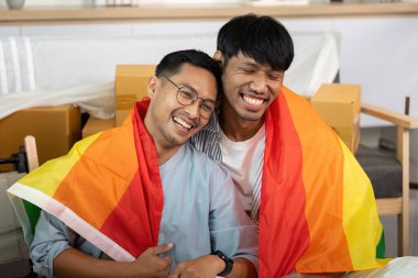 Gökkuşağı bayraklarına sarılmış, gülümseyen ve kucaklayan iki gay, aşklarını kutluyorlar ve LGBTQIA 'nın gururu rahat bir yaşam alanında.