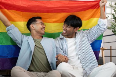 Gökkuşağı bayrağı tutan iki mutlu adam, aşklarını ve kimliklerini kutluyorlar..