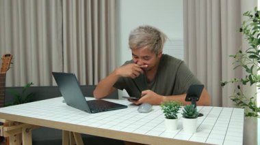 Evde oturan Asyalı bir adam, kendisine verilen bir projenin bütçesini özetlemeye odaklanmıştı. Uzaktan çalışma, sorumluluk ve konsantrasyon gösteriyordu..