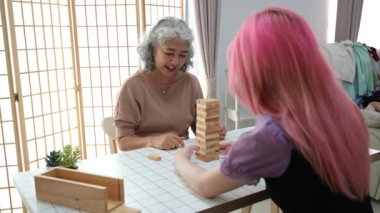 Sevgi dolu bir büyükanne ve torununun oturma odasında klasik bir Jenga oyunu oynarken kahkaha ve neşe paylaştıkları samimi bir birliktelik anı. Nesillerine rağmen