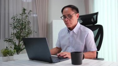 Yaşlı baba emekliliğinin tadını çıkarıyor, son gelişmelerden haberdar olmak için dizüstü bilgisayar kullanıyor, teknoloji ve rahatlamayı kucaklıyor..