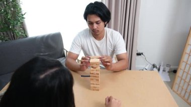 İki Asyalı genç arkadaş, bir erkek ve bir kız, okul molasında birlikte ahşap oyunlar oynayarak eğleniyorlar, kahkaha ve bağlanma anlarını paylaşıyorlar..