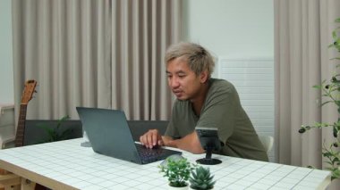 Evde oturan Asyalı bir adam, kendisine verilen bir projenin bütçesini özetlemeye odaklanmıştı. Uzaktan çalışma, sorumluluk ve konsantrasyon gösteriyordu..