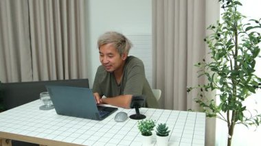 Evde oturan Asyalı bir adam, kendisine verilen bir projenin bütçesini özetlemeye odaklanmıştı. Uzaktan çalışma, sorumluluk ve konsantrasyon gösteriyordu..