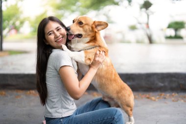 Genç bir kadın, evcil hayvanlarla sahipleri arasındaki duygusal bağı vurgulayarak, Corgisiyle sevgi dolu bir kucaklaşmayı paylaşıyor..