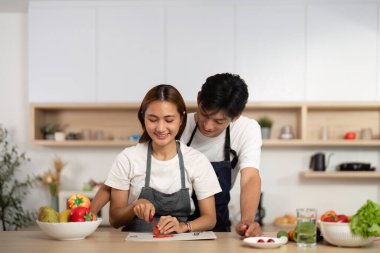 Bir çift, mutfağında taze malzemelere ve takım çalışmasına odaklanmış keyifli bir yemek pişirme deneyimini paylaşıyor..