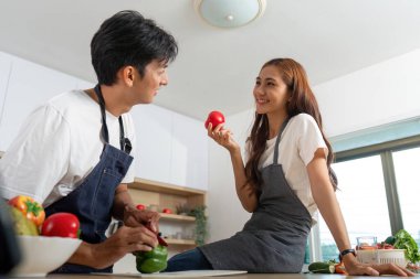 Bir çift, sağlıklı bir yemek hazırlarken taze ürünleri tartışarak mutfakta eğleniyor..