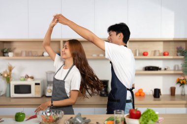 Bir çift, yemek pişirirken, aşklarını ve ilişkilerini paylaşarak, mutfaklarında neşeyle dans eder..