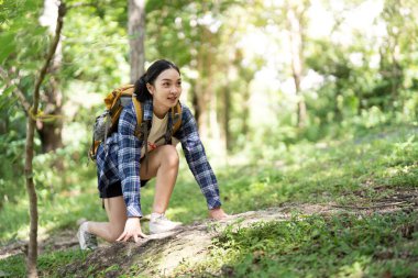 Bir kadın yürüyüşçü kayalık bir patikaya tırmanıyor, doğadaki macera ruhunu ve fiziksel uygunluğu somutlaştırıyor..