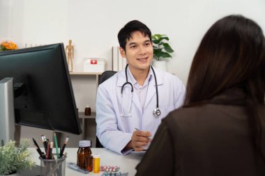 Bir doktor hastasını dikkatle dinler ve onu karşılayan sağlık bürosunda destekleyici ve bilgilendirici bir konsültasyon sağlar..