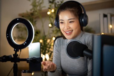 Hevesli genç bir kadın bir podcast kaydederken görüşlerini paylaşıyor, stüdyosunda sıcak ve davetkar bir atmosfer yaratıyor..