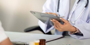 Bir doktor, modern bir klinikte danışmanlık deneyimini geliştirmek ve hasta verilerine erişmek için bir tablet kullanır..