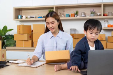 Bir anne çocuğuna bakarken internet işleriyle uğraşır, modern ebeveynlik ve girişimcilik gösterir..